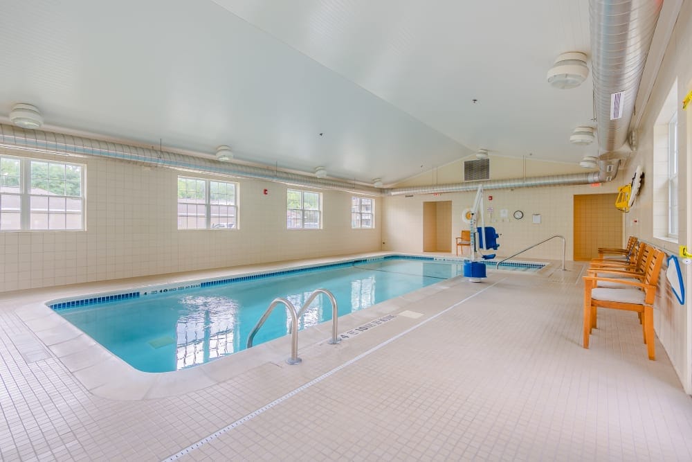 Indoor swimming pool area with chairs and windows