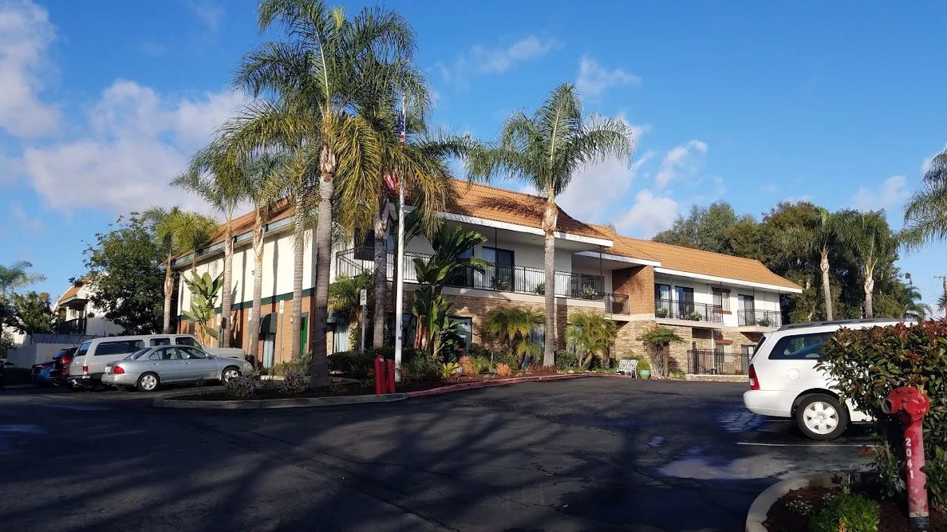 Exterior view of a senior living facility surrounded by palm trees