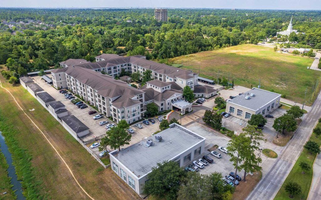 Conservatory at Champion Forest, independent living in Spring, TX — Aerial view of a senior living facility surrounded by greenery
