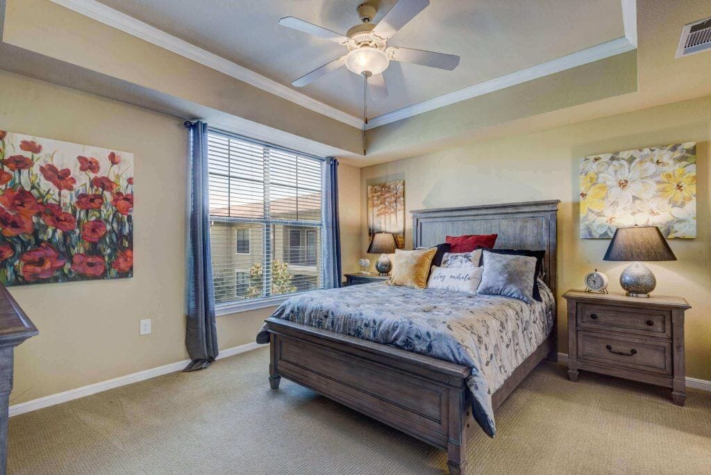 Conservatory at Champion Forest, independent living in Spring, TX — Cozy bedroom with decorative wall art and natural light