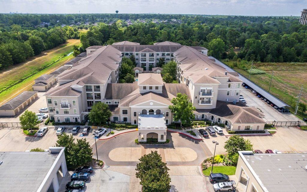 Conservatory at Champion Forest, independent living in Spring, TX — Aerial view of a senior living facility surrounded by trees