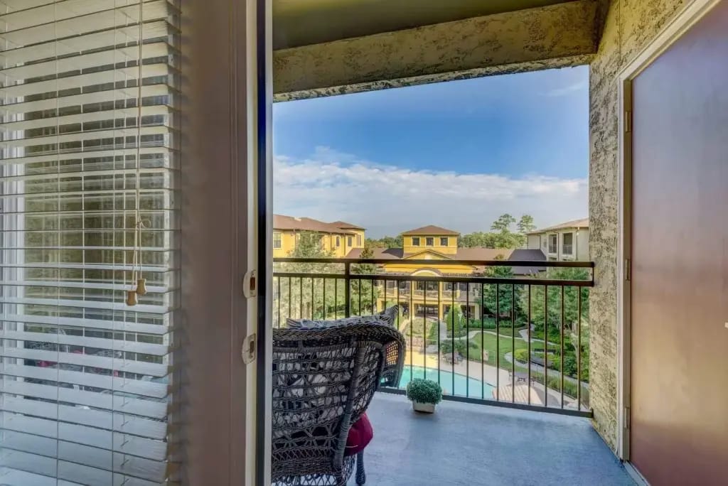 Conservatory at Champion Forest, independent living in Spring, TX — Balcony view overlooking a landscaped courtyard and pool