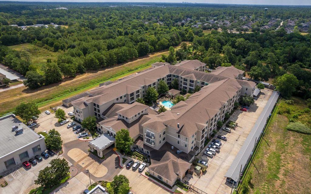 Conservatory at Champion Forest, independent living in Spring, TX — Aerial view of a senior living facility with a pool