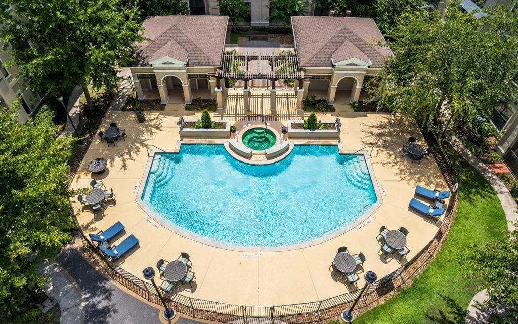 Conservatory at Champion Forest, independent living in Spring, TX — Resort-style swimming pool surrounded by lounge chairs and greenery