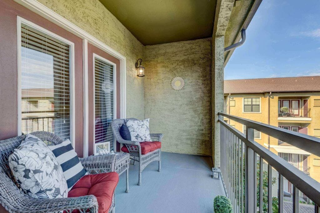 Conservatory at Champion Forest, independent living in Spring, TX — Porch with seating and decorative elements overlooking a courtyard