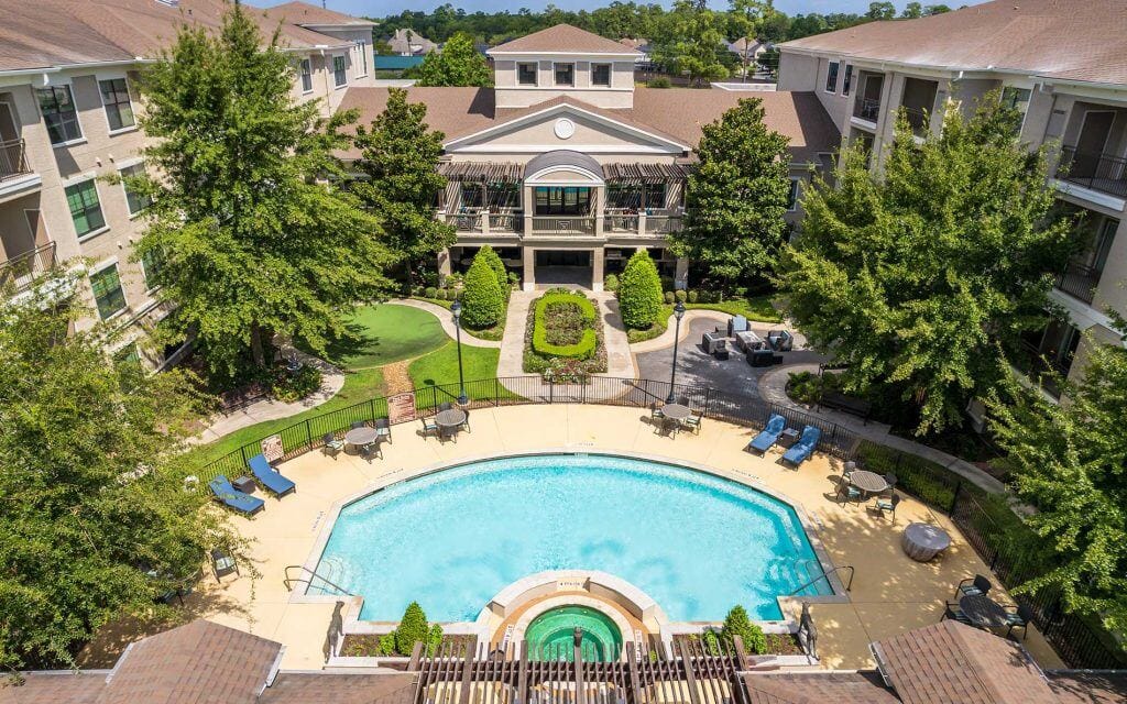 Conservatory at Champion Forest, independent living in Spring, TX — Aerial view of a serene pool surrounded by greenery