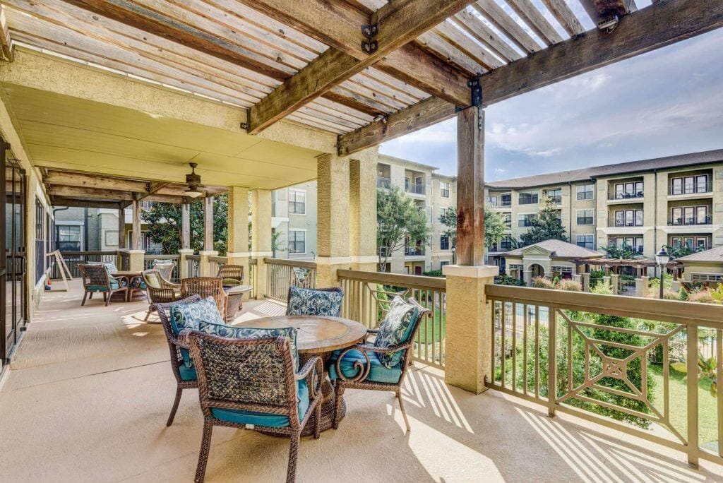 Conservatory at Champion Forest, independent living in Spring, TX — Outdoor seating area with tables and chairs overlooking gardens