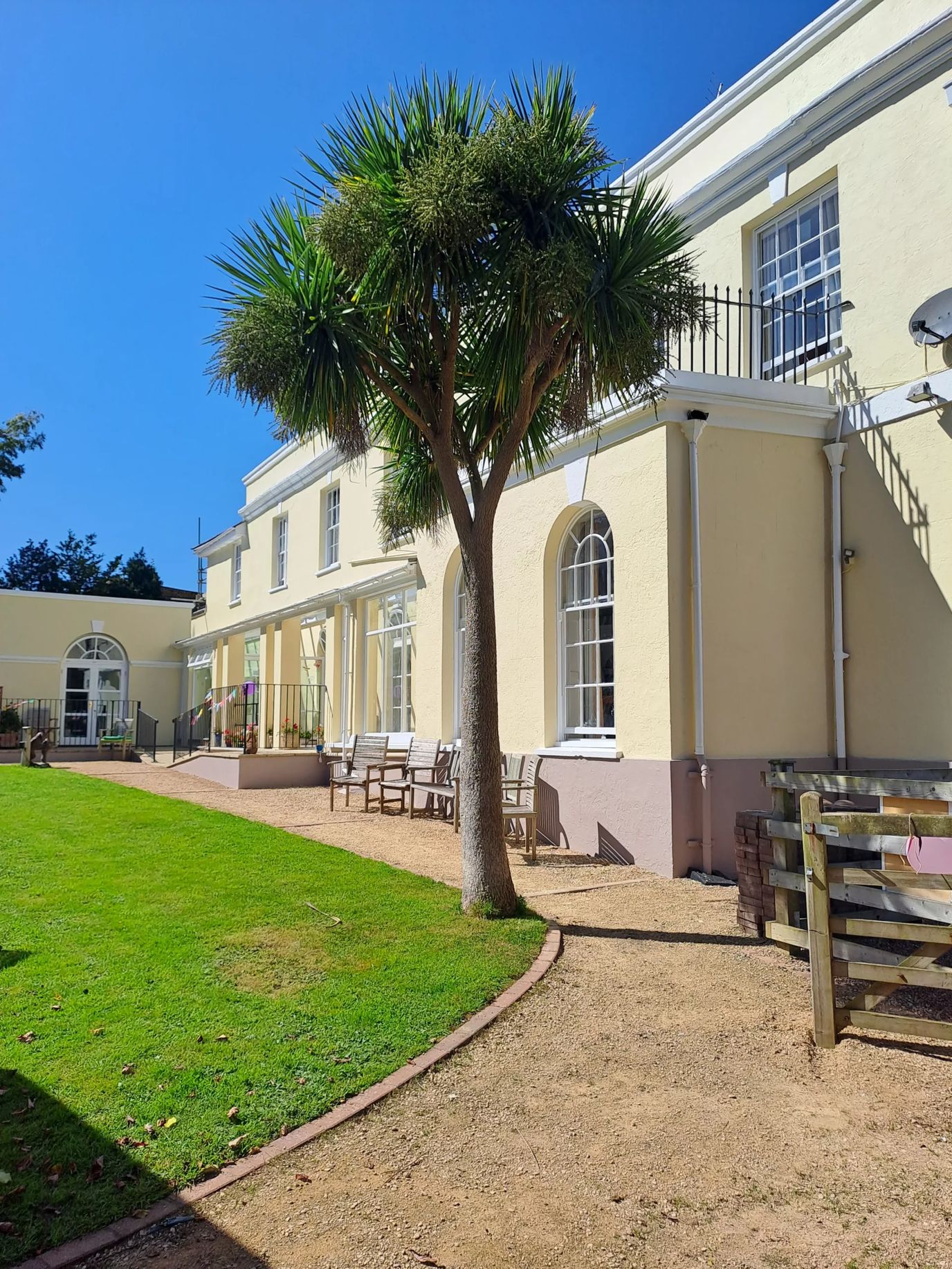 Exterior view of Arcot House Care Home with a palm tree