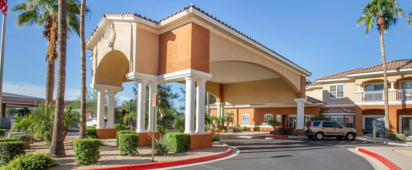 Entrance of a senior living facility with palm trees