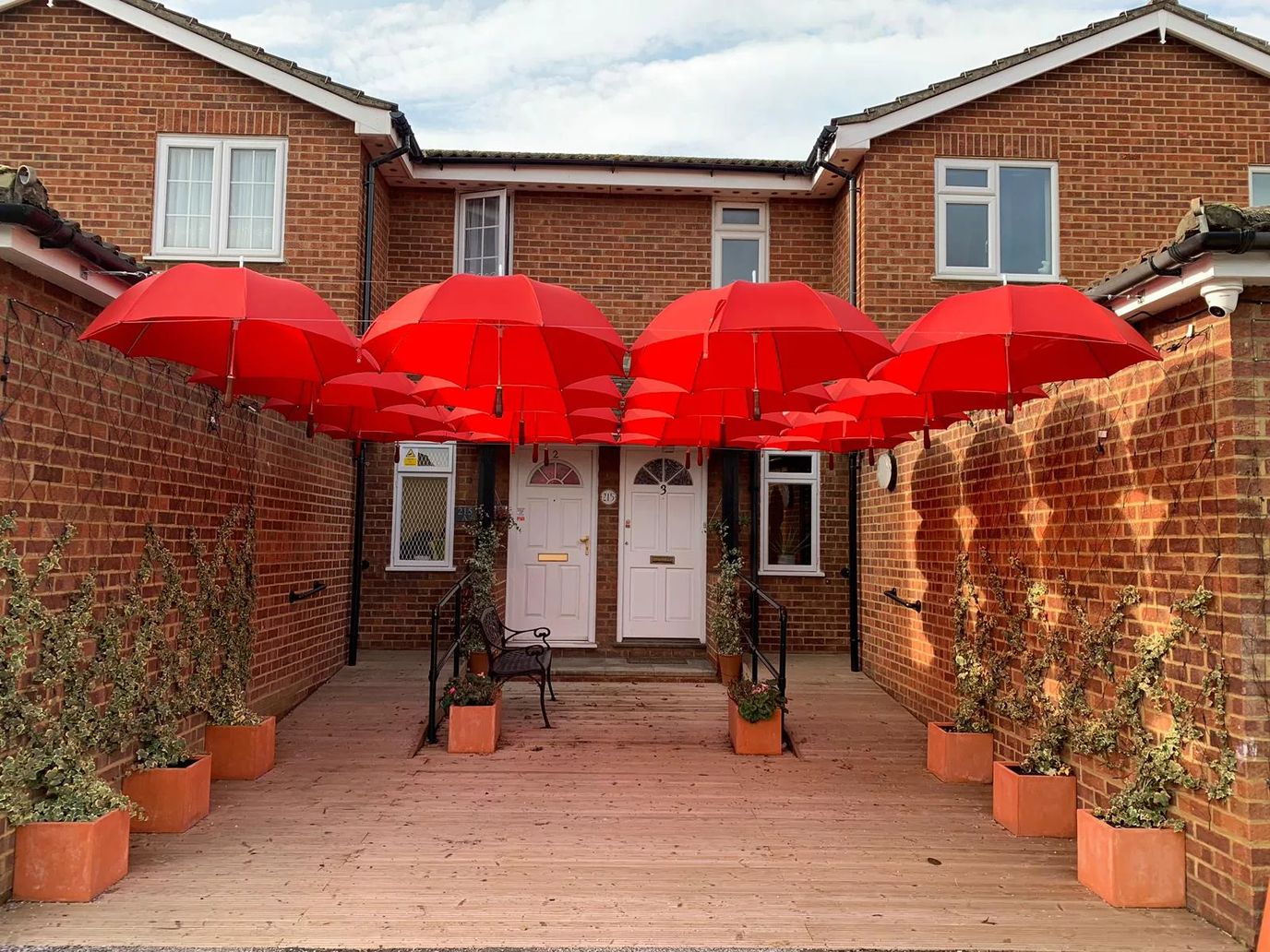 Entrance with red umbrellas and planters.