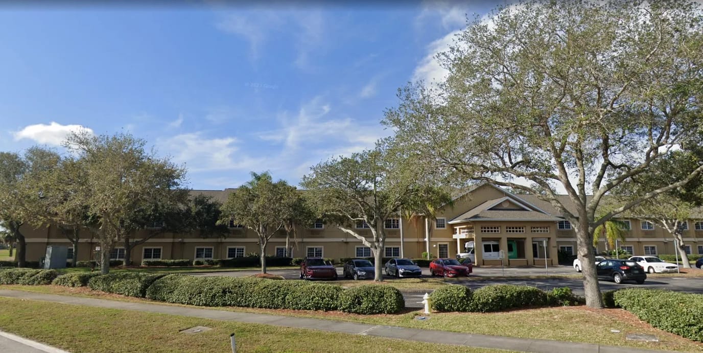 Exterior view of Greenwood Place facility with trees and parking