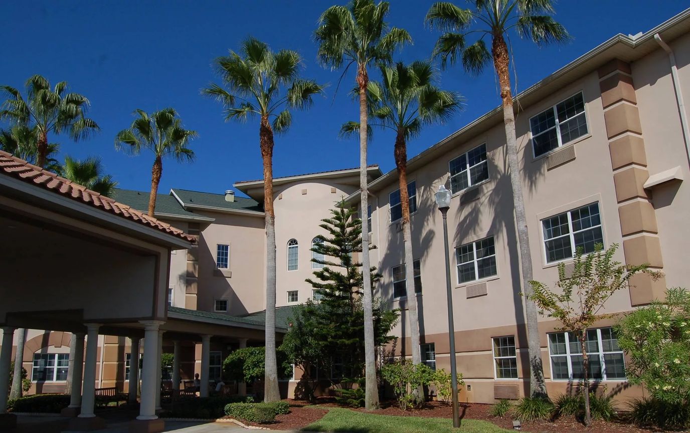 Exterior view of a senior living facility surrounded by palm trees