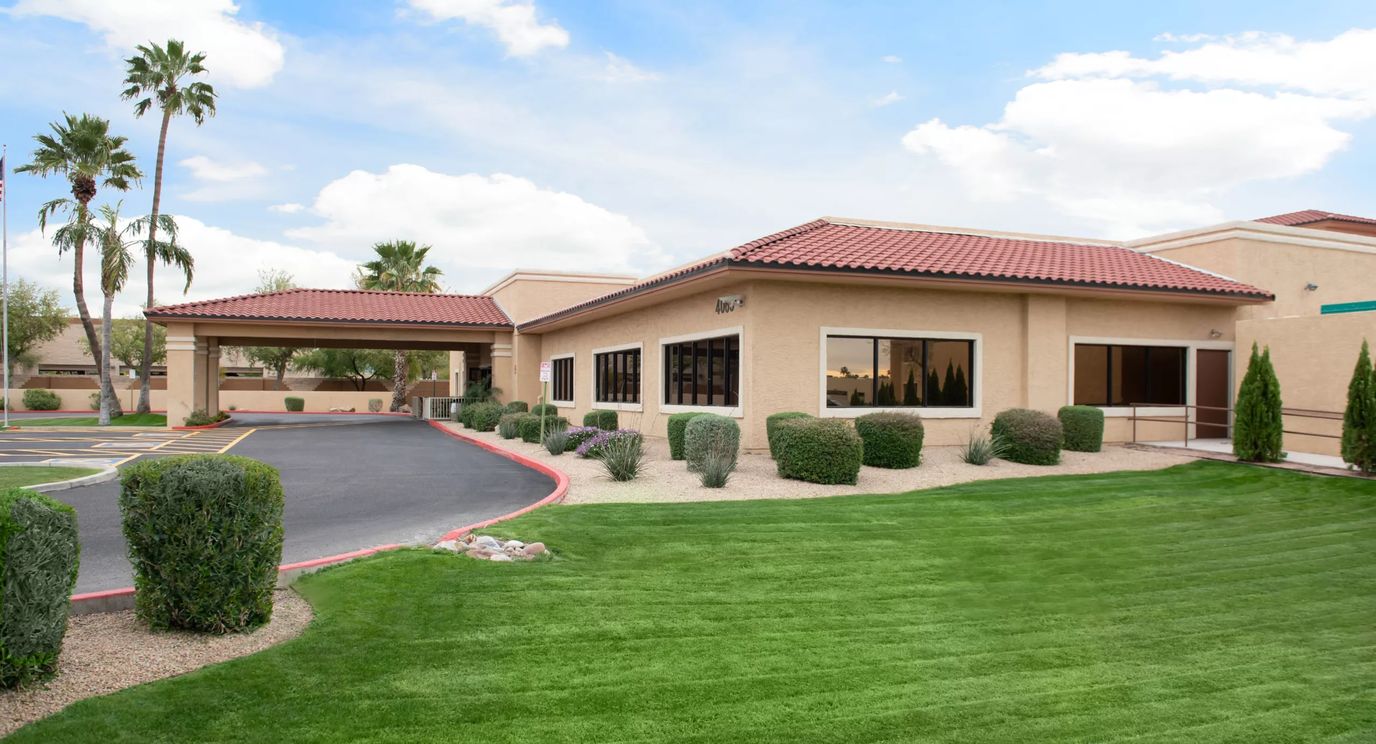 Building exterior with landscaped lawn and palm trees