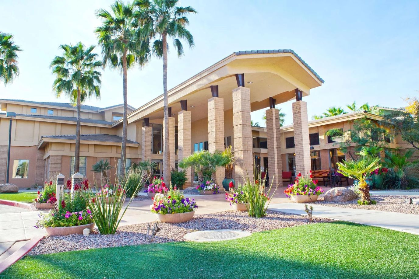 Exterior view of a senior living facility with palm trees and flowers