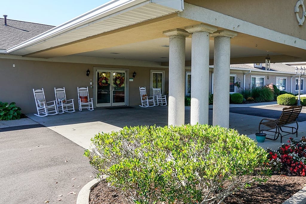 Covered outdoor area with rocking chairs and landscaping