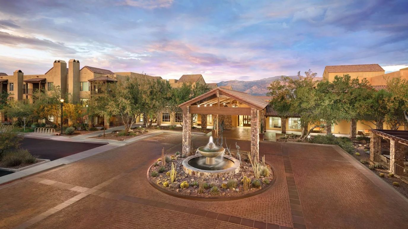 Exterior view of a senior living facility with garden and fountain