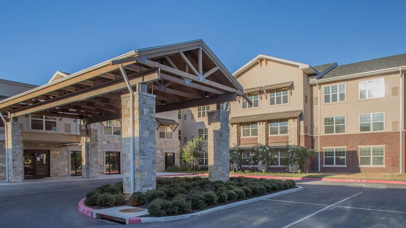 Exterior view of senior living facility entrance with covered drive