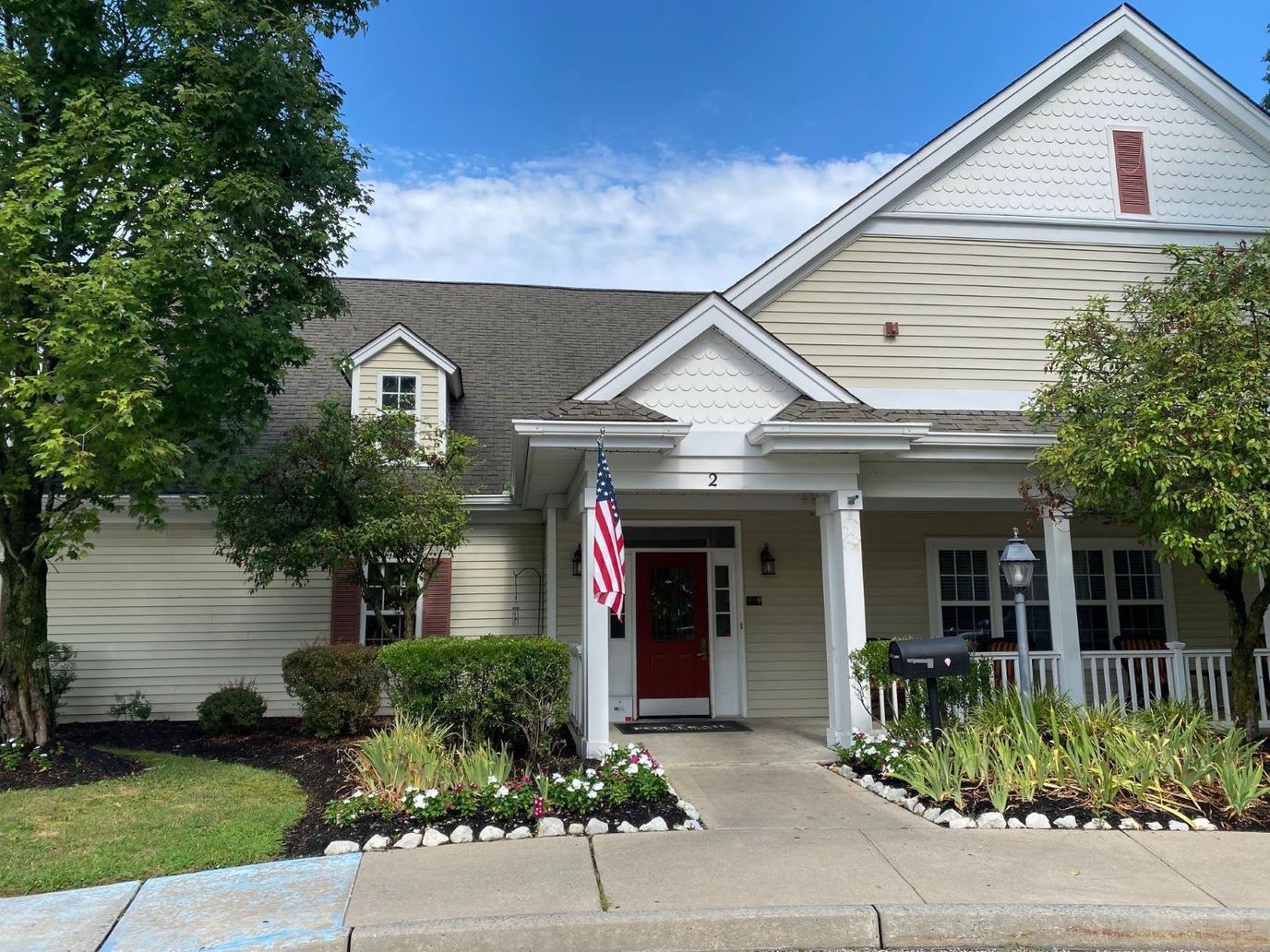 Exterior view of a senior living facility with flowers and an American flag