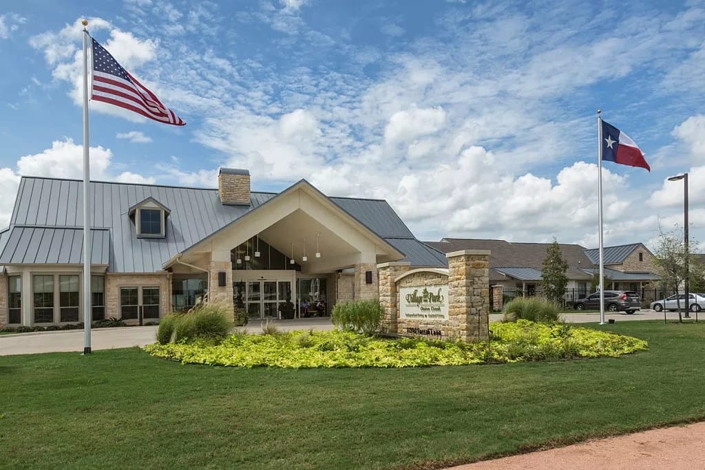 Front exterior of Village on the Park Onion Creek with flags