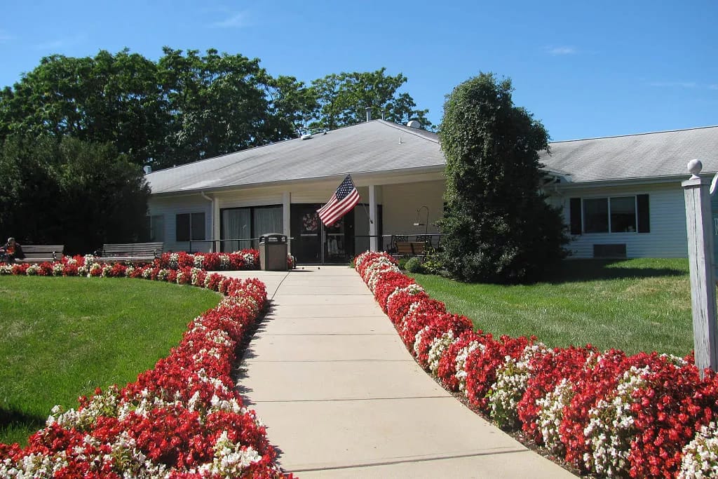 Exterior view of an assisted living facility with a flower-lined walkway