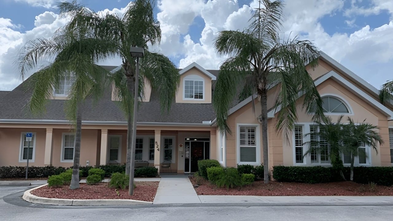 Exterior view of a senior living facility surrounded by palm trees