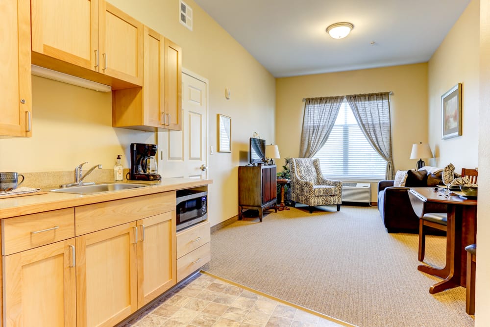 Cozy resident room with kitchenette and seating area.