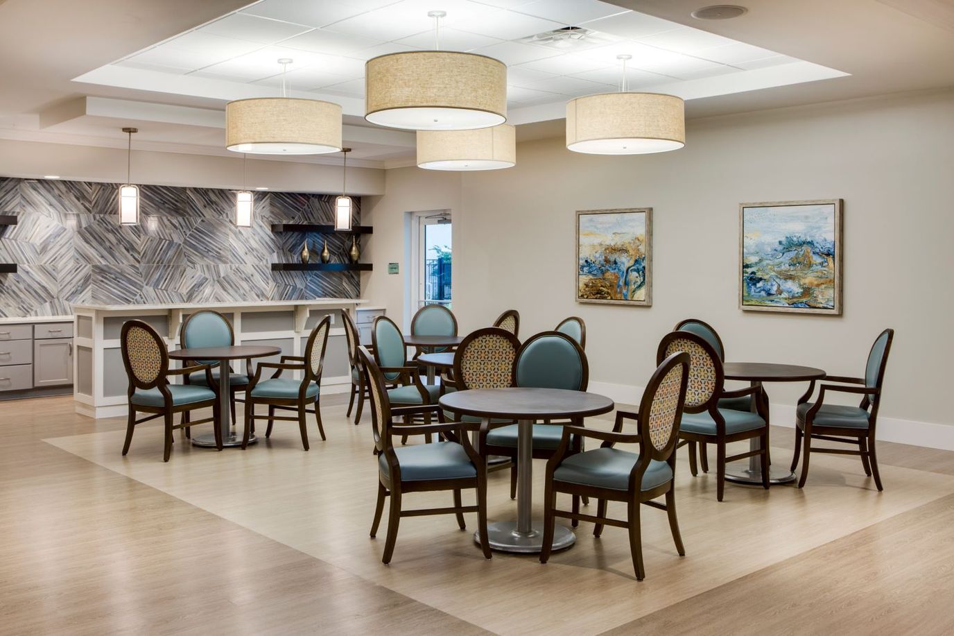A modern common area with tables and chairs at Heritage Oaks of Englewood