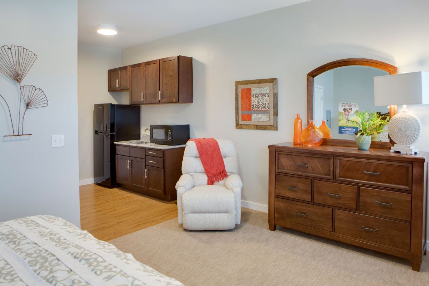 A well-furnished living space with kitchenette, recliner, and decorative accents.