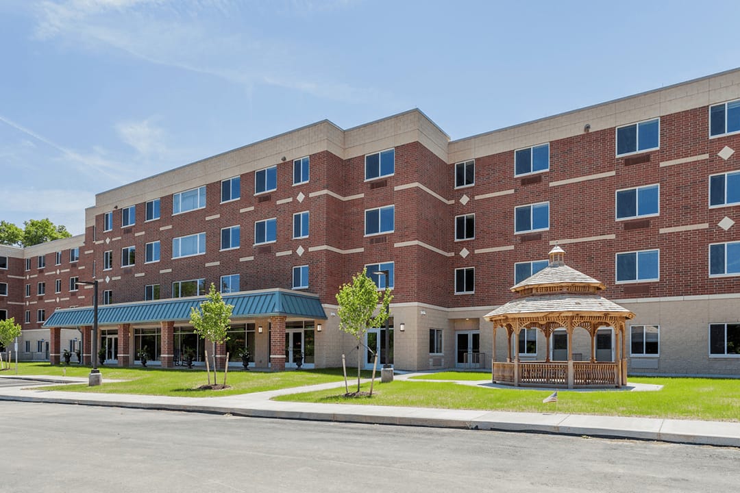 Exterior view of a senior living facility with a garden gazebo