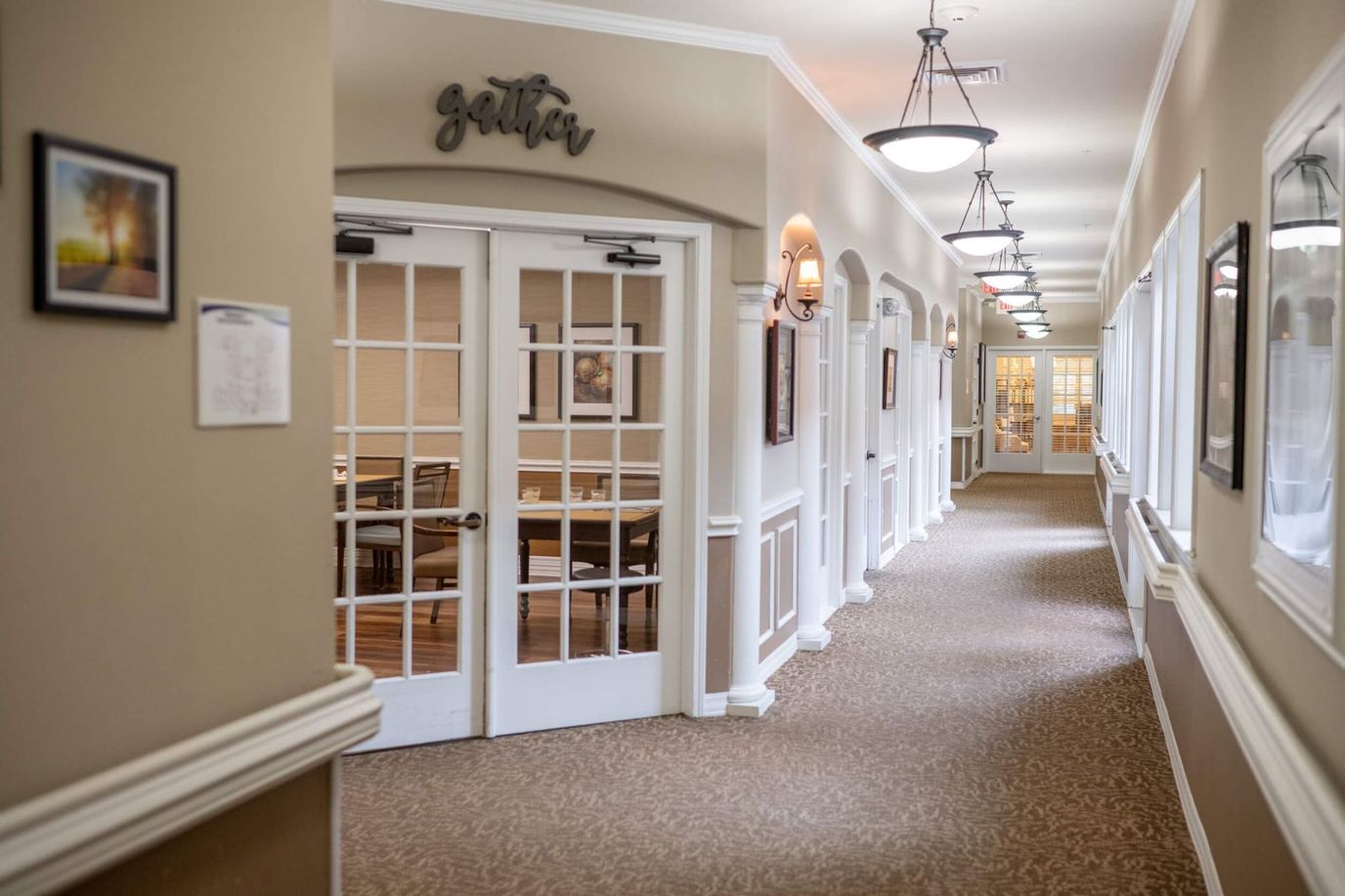 Heritage at Eldridge Parkway, memory care in Houston, TX — Brightly lit corridor with dining area entrance and artwork