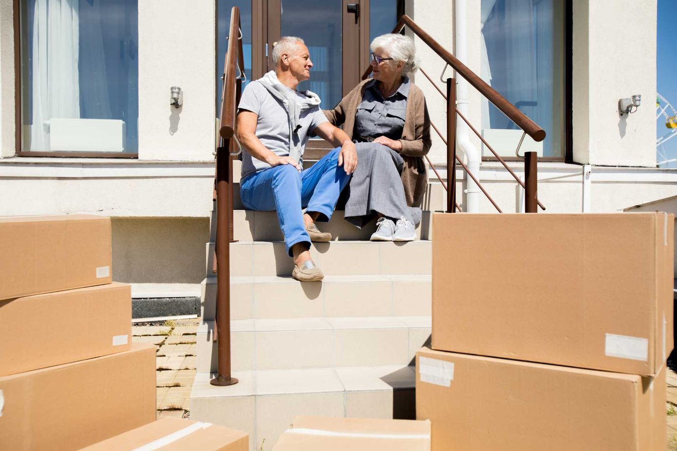 Two residents sitting on steps with moving boxes nearby