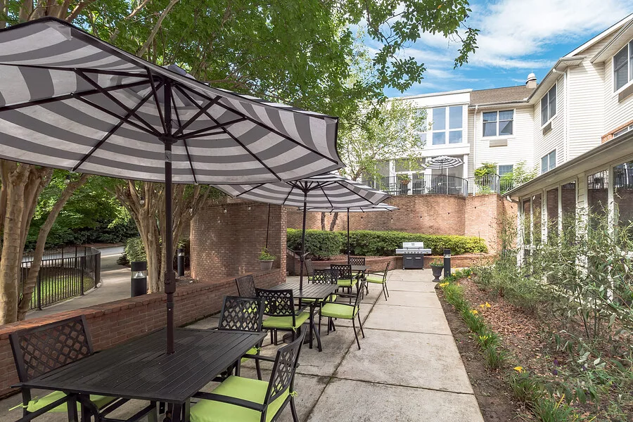 Outdoor patio with tables and umbrellas at The Parker senior living facility.