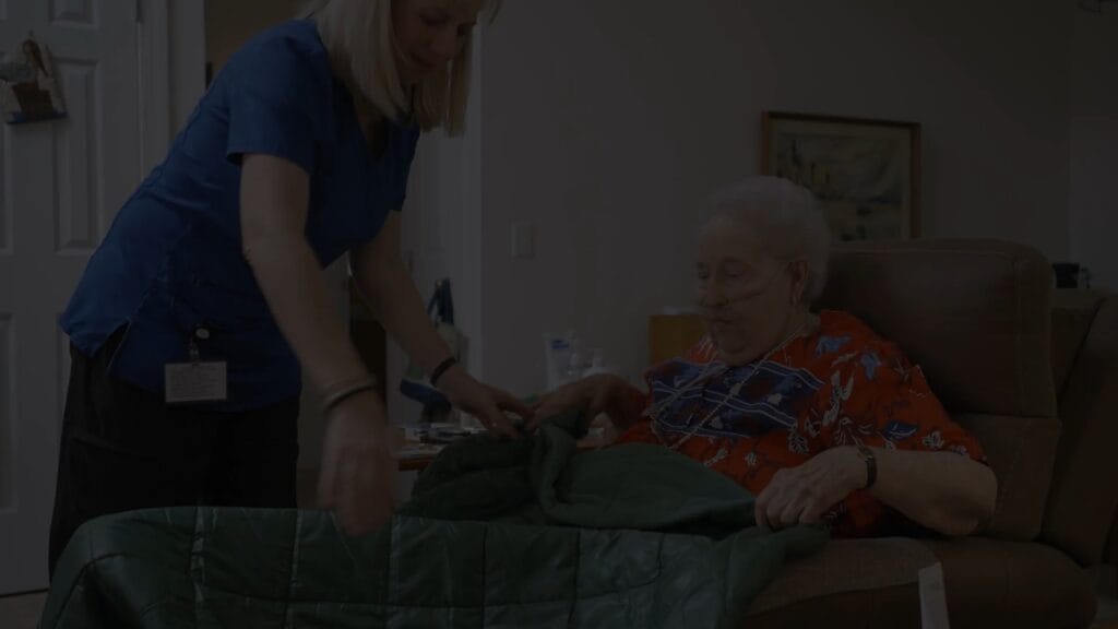Staff assisting a resident with a blanket.