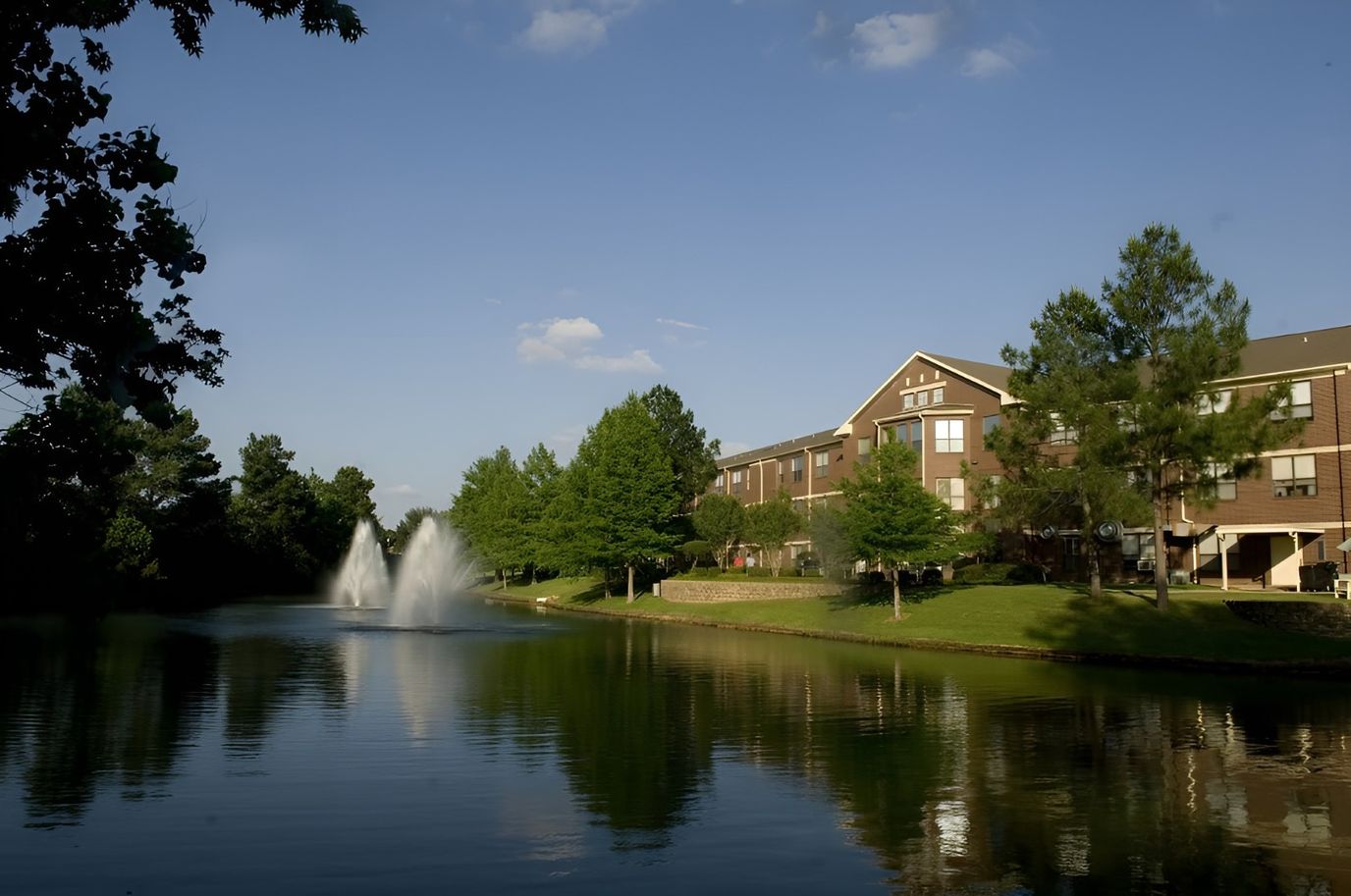 Scenic view of a pond with a fountain and the facility in the background