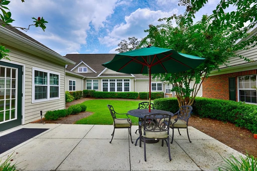 Columbia Cottage Mountain Brook, assisted living in Birmingham, AL — Patio seating area with green umbrella and landscaped garden