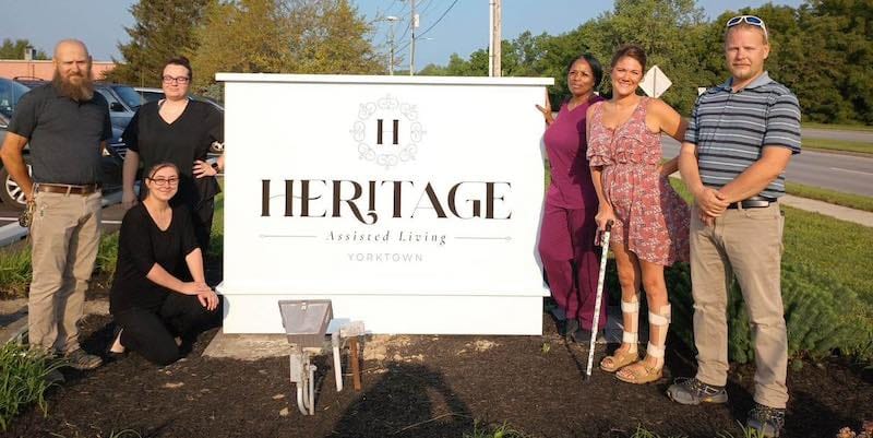 Group of staff members in front of Heritage Assisted Living sign