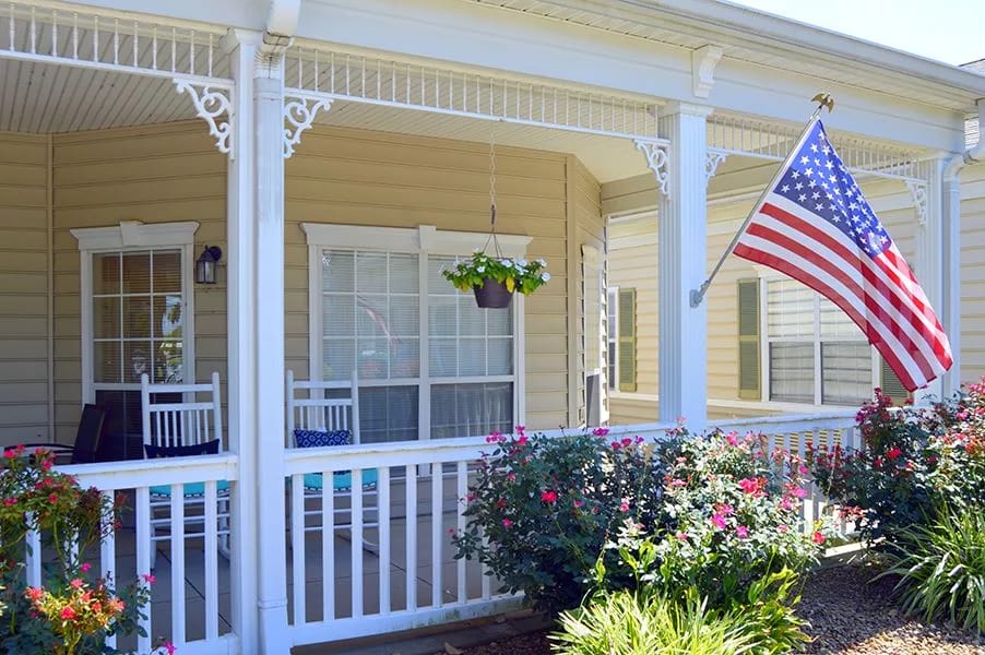 Porch with rocking chairs and American flag at Heritage Place