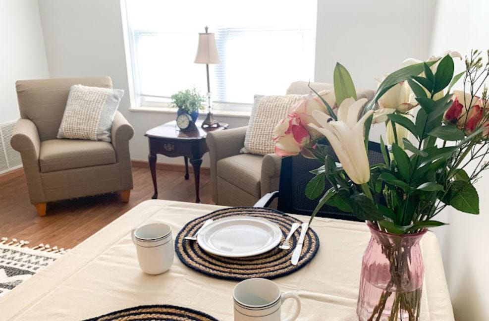 Cozy dining area with floral centerpiece, table setting, and two armchairs