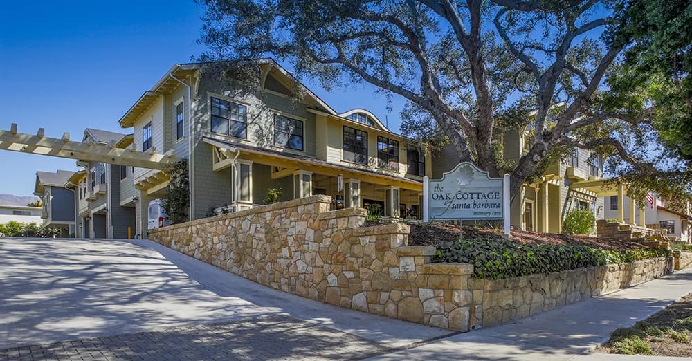 Exterior view of Oak Cottage of Santa Barbara with stone wall and trees.