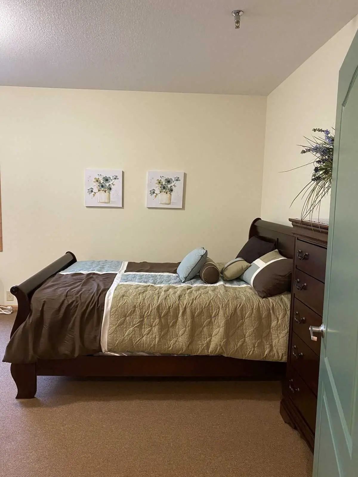 A well-decorated bedroom featuring a bed with a quilt and decorative pillows.