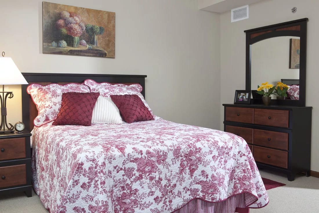 A cozy bedroom with floral bedding and a mirror