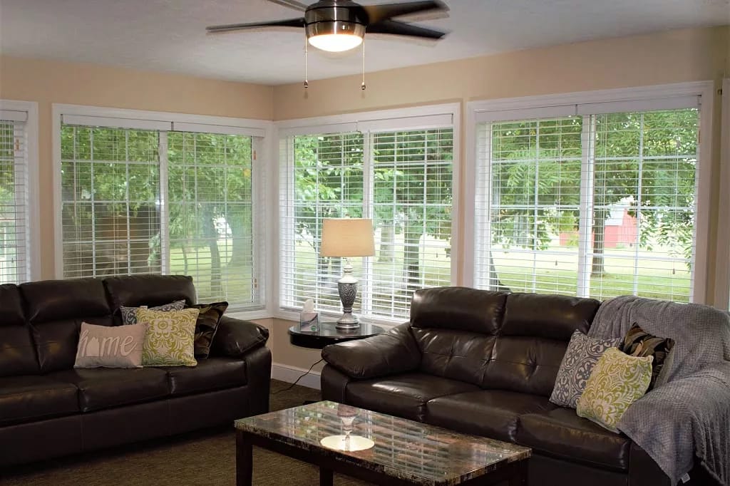 Spacious living room with two dark couches and large windows.