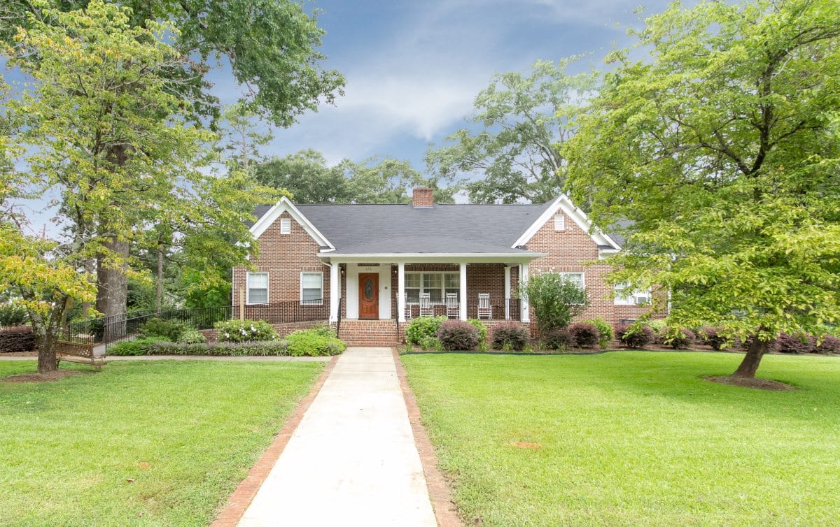 Exterior view of a brick house surrounded by trees