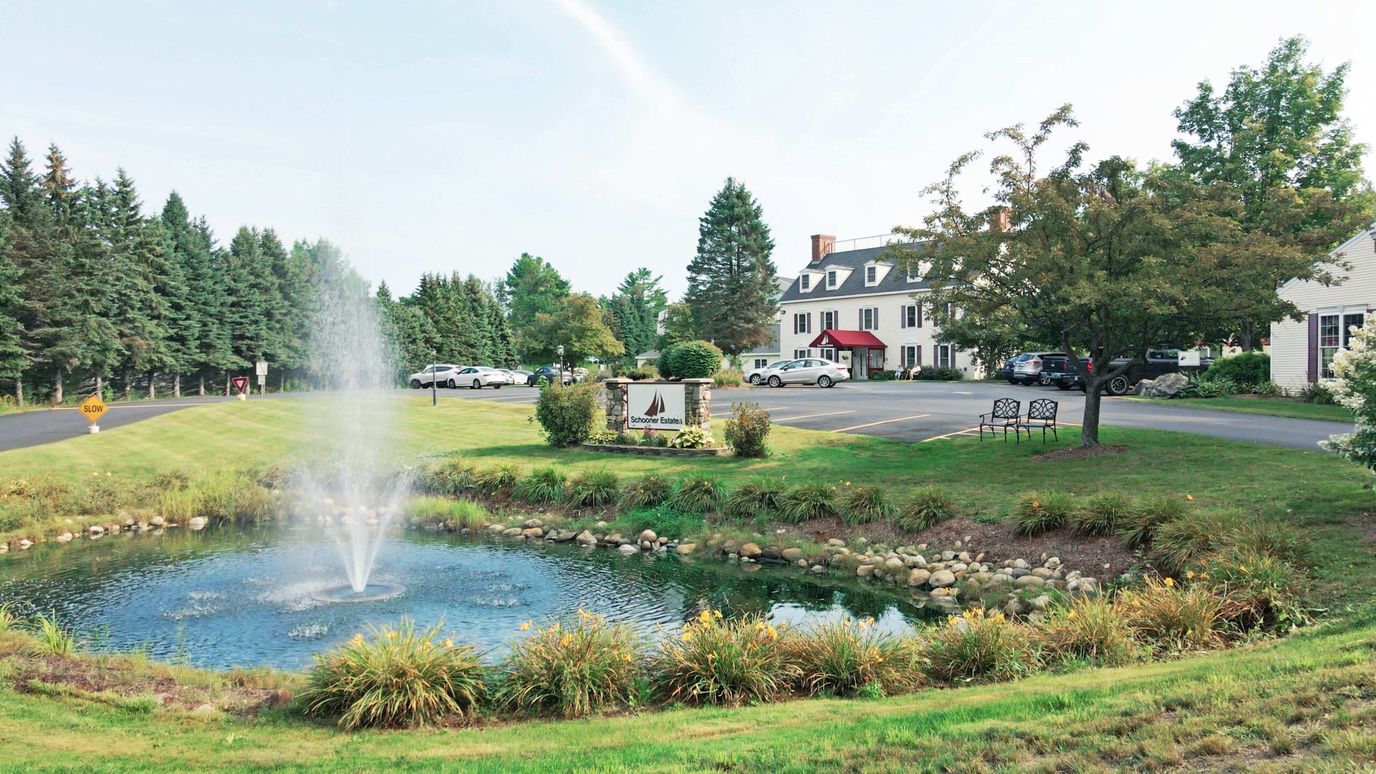 Exterior view of Schooner Estates Senior Living with a fountain