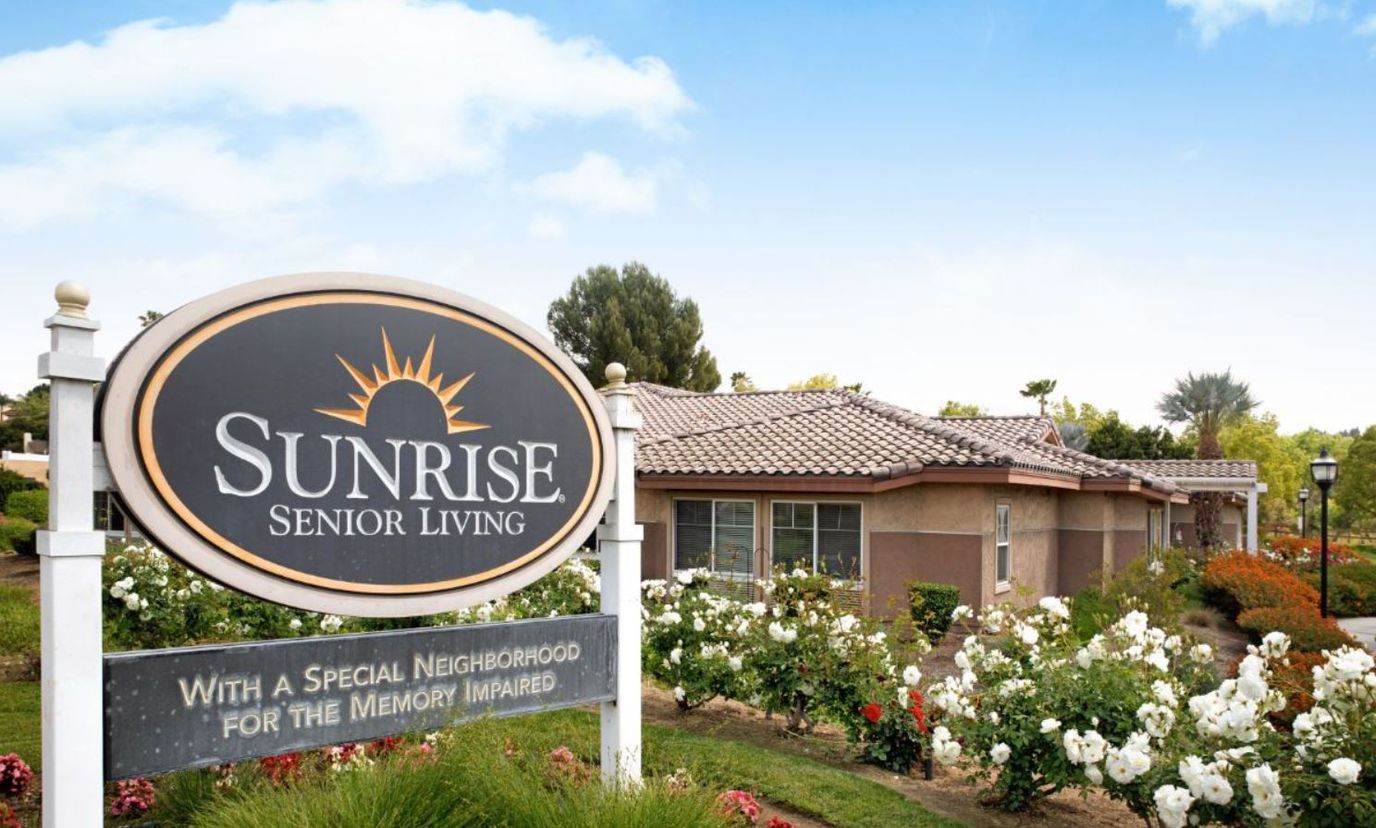 Exterior view of Sunrise Senior Living facility with gardens