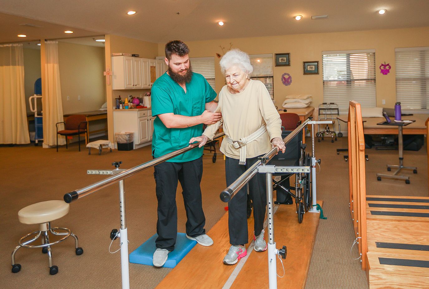 Staff assisting a resident with mobility in the facility's therapy room