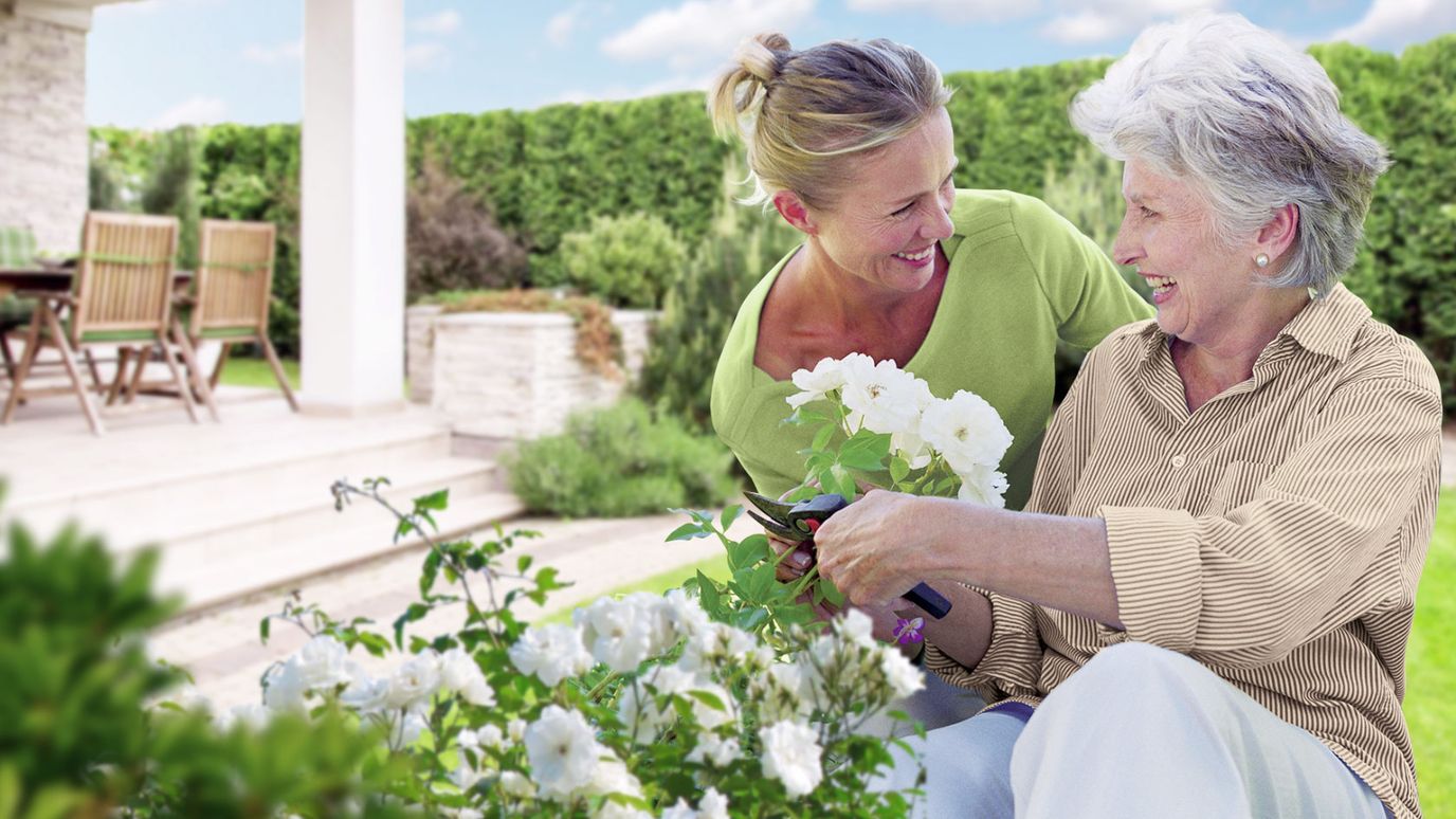 A caregiver and resident gardening together outdoors