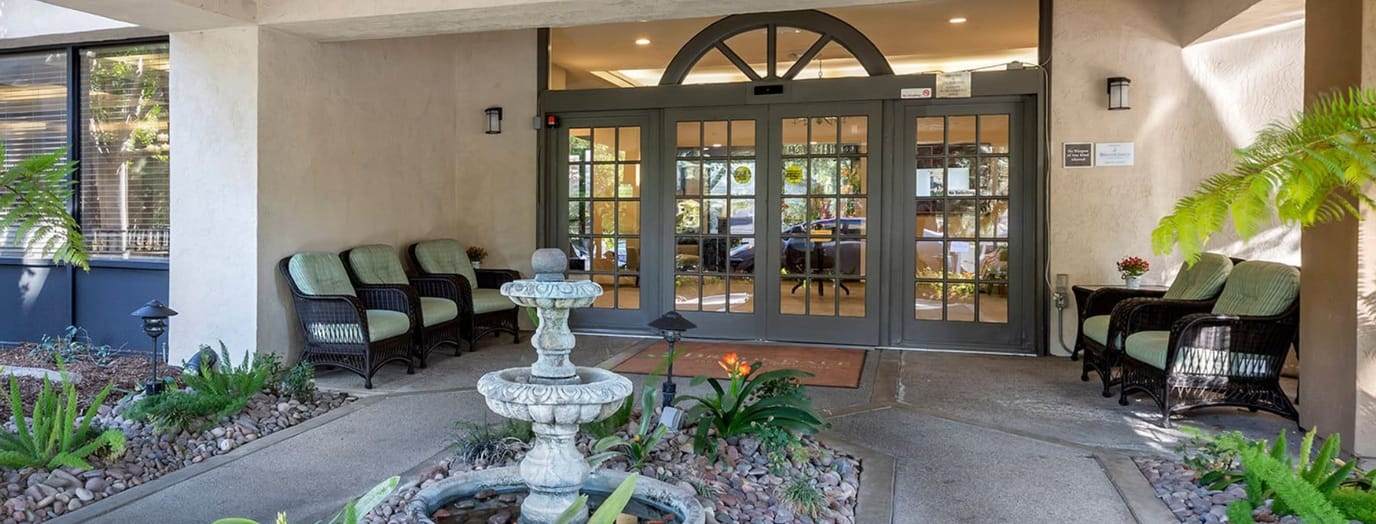 Entrance of a senior living facility with seating and fountain