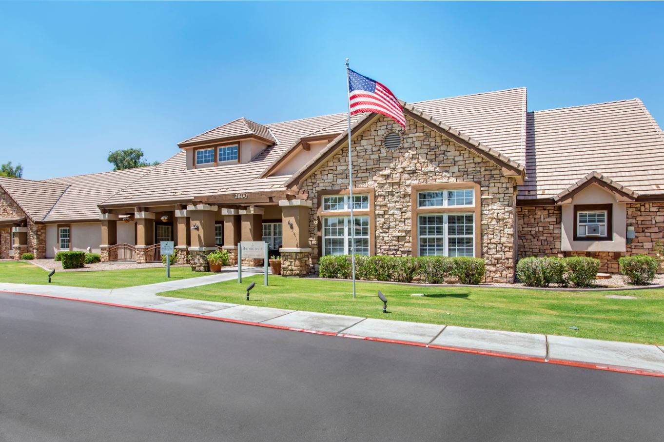 Front exterior of a senior living facility with a flag
