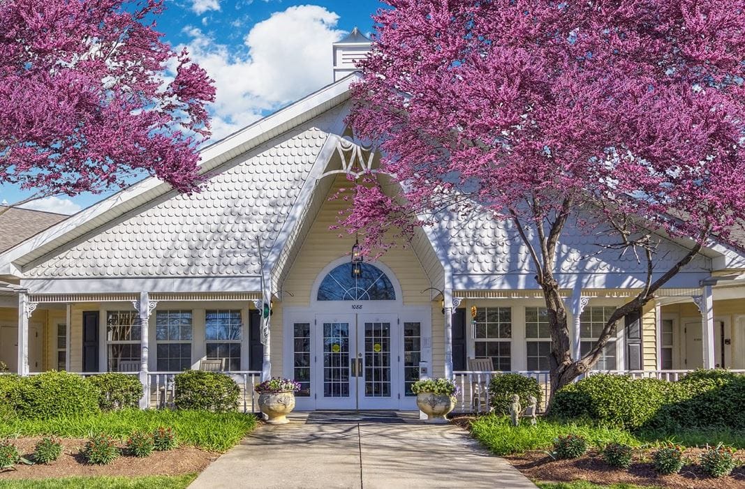 Front entrance of a senior living facility surrounded by blooming trees